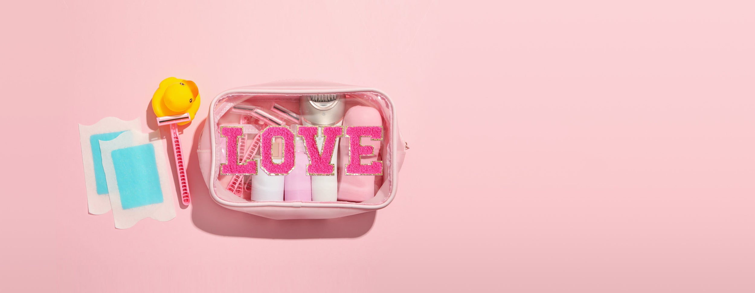 A pink transparent makeup bag with pink chenille letter patches spelling 'LOVE,' surrounded by beauty accessories including a yellow duck razor and blue wax strips. Text on the side reads 'Beauty in Every Detail, Style in Every Patch!'